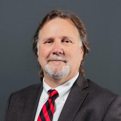 Headshot of RC Andersen Employee, Vice President, Eddie Slay in a suit and red/black striped tie