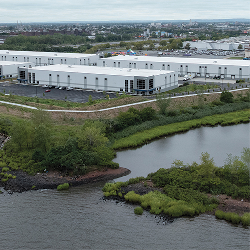 Aerial/drone image of the four-building, industrial campus with water to the left and right of the site