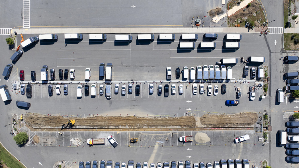 Birdseye view, drone image of a EV-charging retrofit project in-progress with delivery vehicles lining up around construction